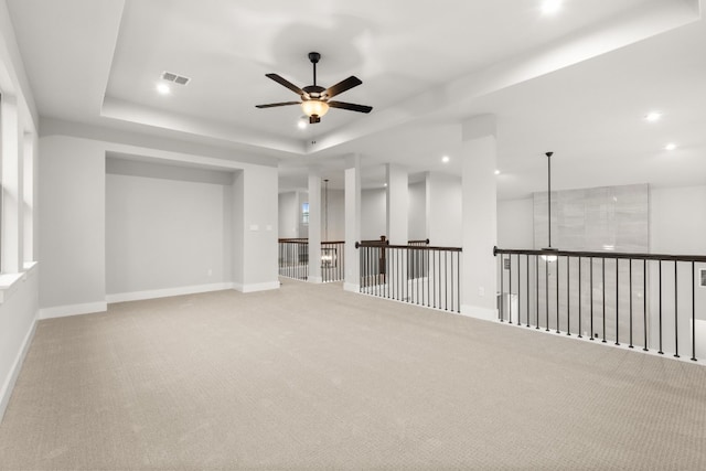 empty room with carpet flooring, ceiling fan, and a tray ceiling