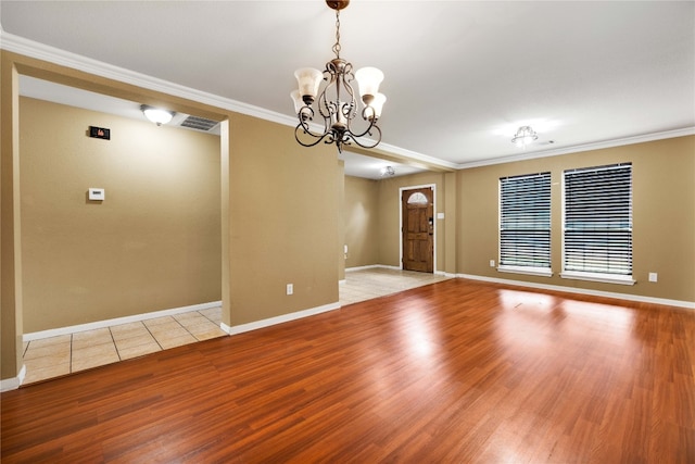 spare room featuring light hardwood / wood-style flooring, an inviting chandelier, and ornamental molding