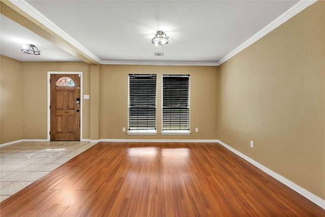 entryway featuring ornamental molding, light hardwood / wood-style floors, and a textured ceiling