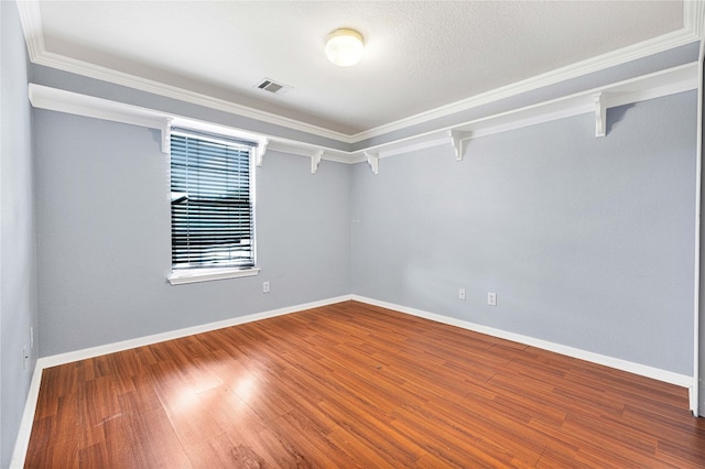 empty room with ornamental molding, a textured ceiling, and hardwood / wood-style floors