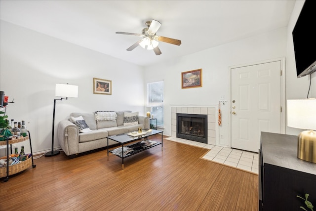 living room featuring ceiling fan, a tile fireplace, and hardwood / wood-style flooring