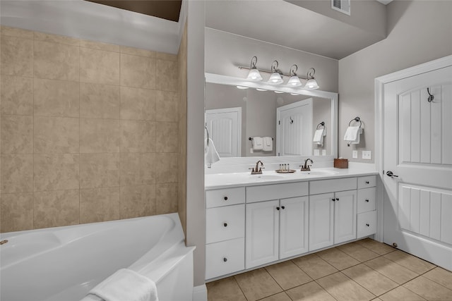 bathroom with a bathing tub, vanity, and tile patterned floors