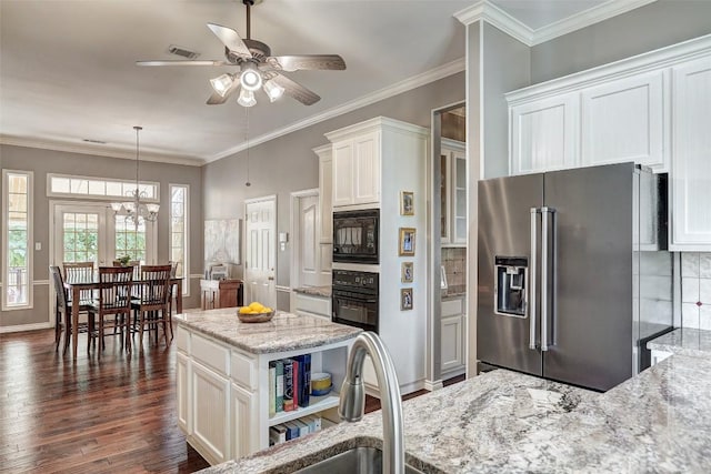 kitchen with light stone counters, black appliances, a kitchen island, pendant lighting, and white cabinets