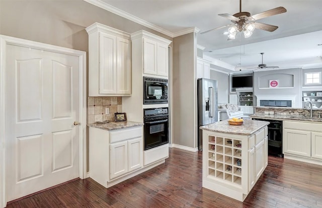 kitchen featuring a center island, white cabinets, light stone counters, and black appliances