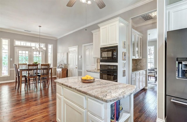 kitchen featuring dark wood-type flooring, white cabinetry, a center island, black appliances, and decorative backsplash