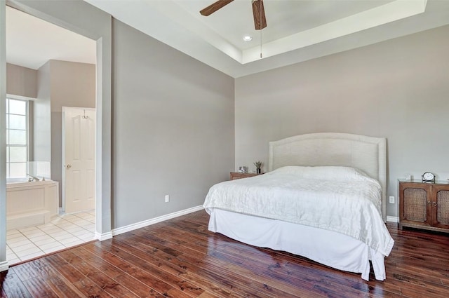 bedroom with a raised ceiling, hardwood / wood-style floors, and ceiling fan