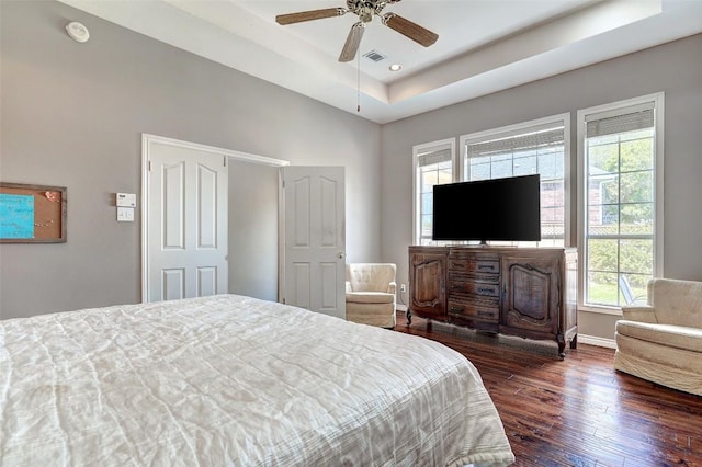 bedroom with dark wood-type flooring, ceiling fan, and a raised ceiling