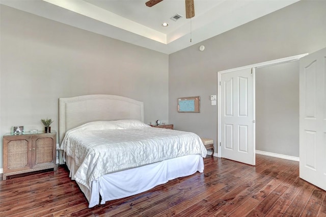 bedroom featuring ceiling fan, dark hardwood / wood-style floors, and a raised ceiling