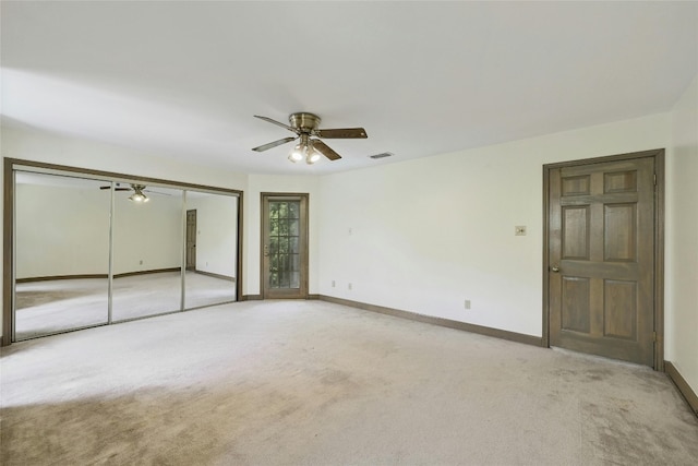 unfurnished bedroom featuring light carpet, ceiling fan, and a closet