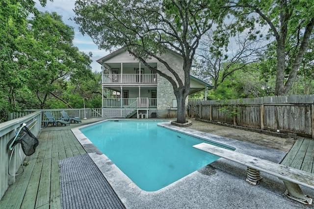 view of pool with ceiling fan, a deck, and a diving board