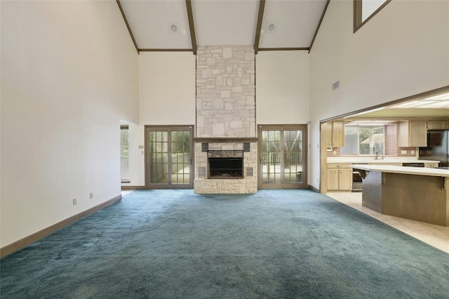 unfurnished living room featuring a fireplace, beamed ceiling, light colored carpet, and high vaulted ceiling