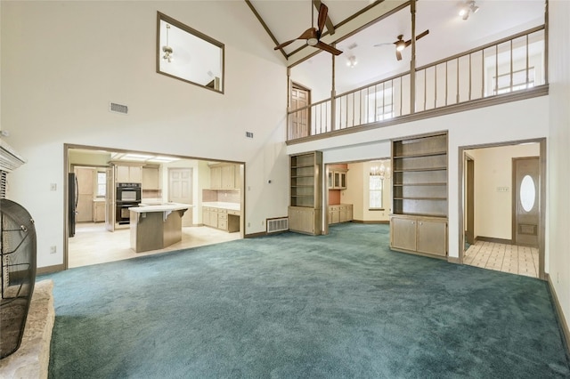 unfurnished living room featuring ceiling fan, built in shelves, carpet, and high vaulted ceiling