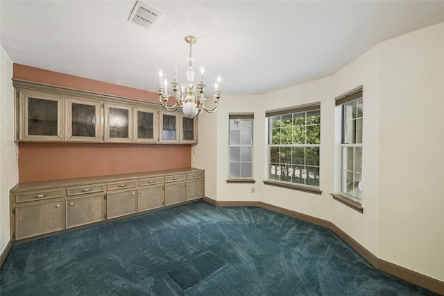 carpeted empty room with an inviting chandelier