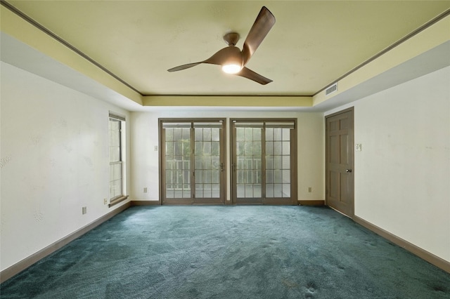 unfurnished room with a tray ceiling, dark colored carpet, and ceiling fan