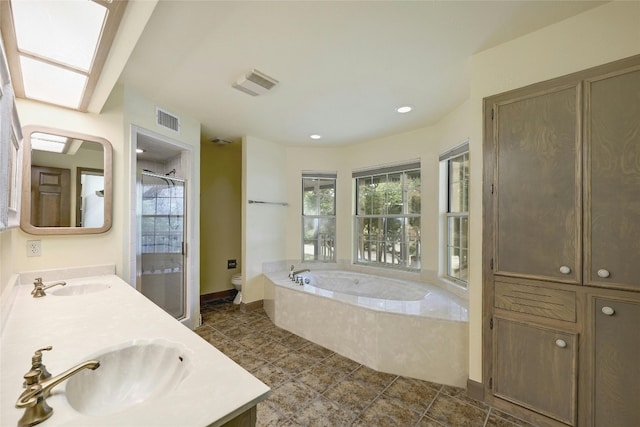 full bathroom featuring vanity, a skylight, shower with separate bathtub, toilet, and tile patterned floors