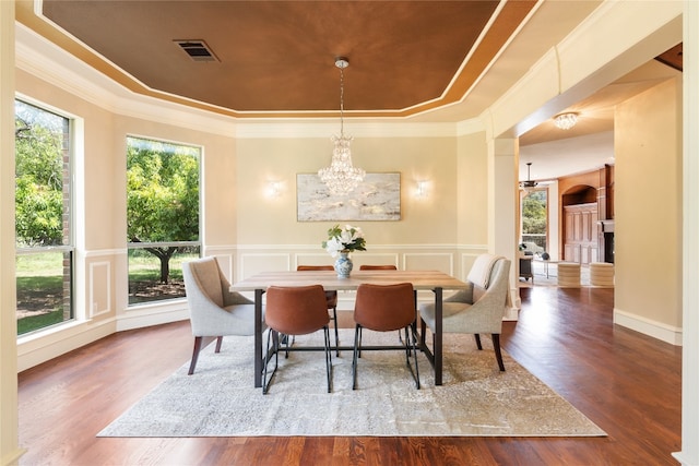 dining area featuring ornamental molding, an inviting chandelier, a tray ceiling, and hardwood / wood-style flooring