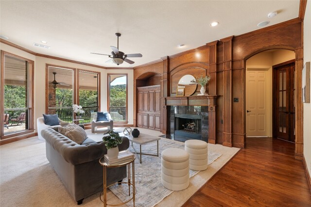 living room with hardwood / wood-style floors, ceiling fan, a fireplace, and crown molding