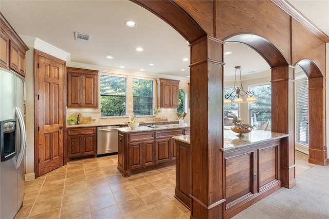 kitchen with pendant lighting, a chandelier, light stone counters, a kitchen island, and appliances with stainless steel finishes