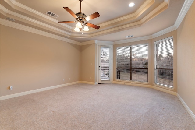 empty room with ceiling fan, light colored carpet, a tray ceiling, and crown molding