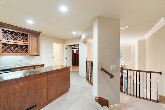 kitchen with light carpet, crown molding, and sink