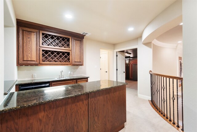 bar with dishwashing machine, dark stone countertops, sink, and light carpet