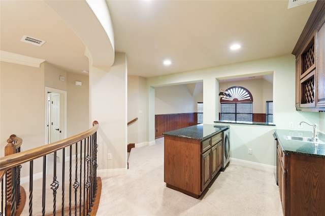 kitchen featuring kitchen peninsula, ornamental molding, sink, and light carpet