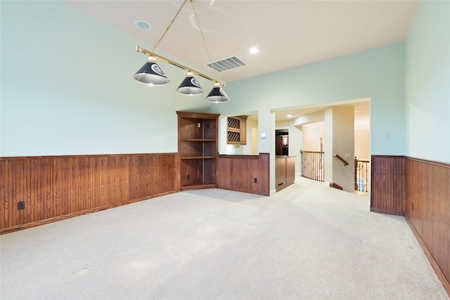 carpeted spare room with wood walls