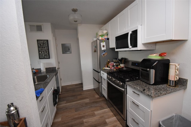 kitchen with dark stone counters, dark hardwood / wood-style floors, sink, white cabinets, and appliances with stainless steel finishes