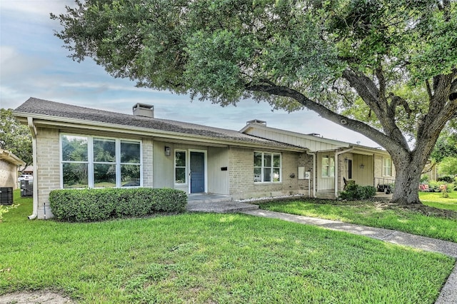 ranch-style home with a front lawn and central AC unit