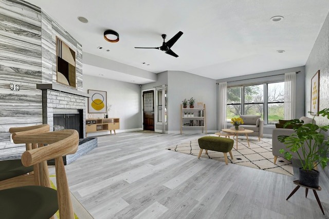 living room featuring a brick fireplace, light hardwood / wood-style floors, and ceiling fan