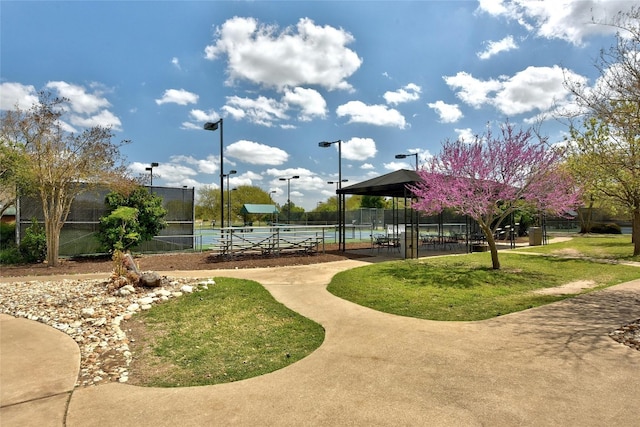 view of property's community with tennis court and a yard