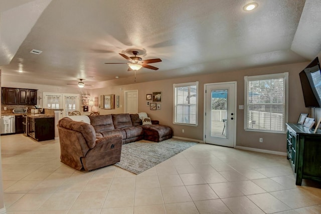 living room with ceiling fan, french doors, vaulted ceiling, a textured ceiling, and light tile patterned floors