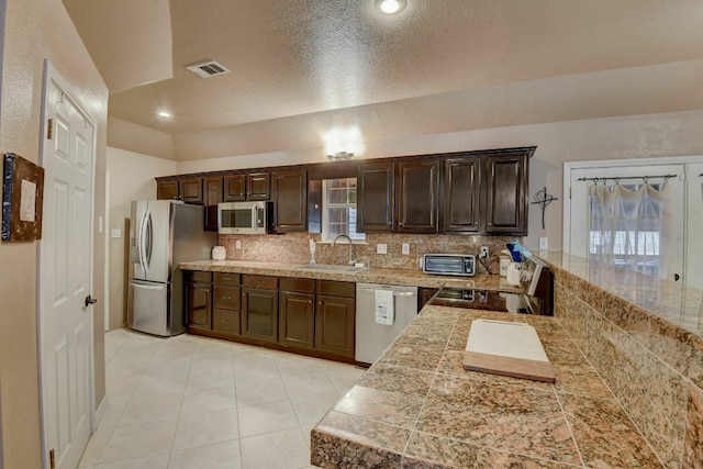 kitchen featuring a textured ceiling, sink, dark brown cabinetry, and stainless steel appliances