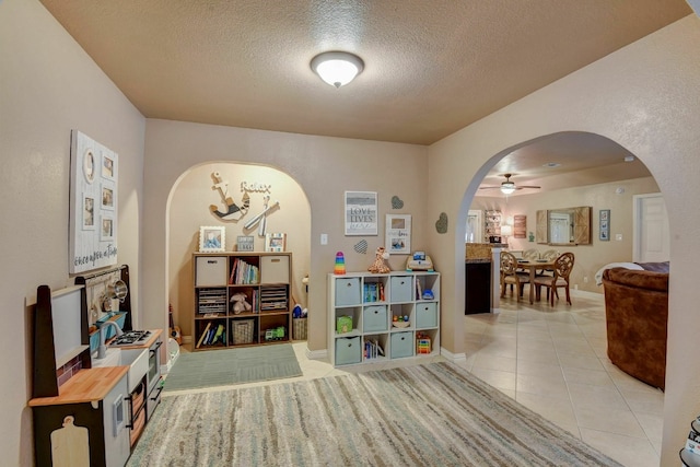 interior space with ceiling fan, light tile patterned floors, and a textured ceiling