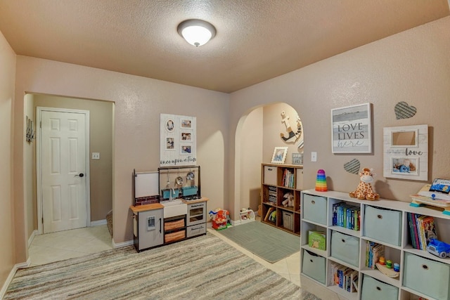 rec room featuring light tile patterned floors and a textured ceiling