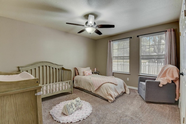 carpeted bedroom featuring ceiling fan and a textured ceiling