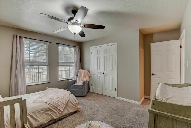 bedroom with ceiling fan, light colored carpet, a textured ceiling, and a closet