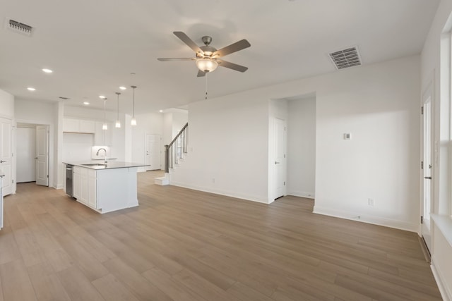 unfurnished living room featuring light hardwood / wood-style flooring, ceiling fan, and sink