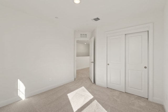 unfurnished bedroom featuring light carpet and a closet