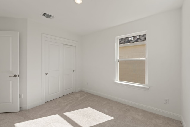 unfurnished bedroom featuring multiple windows, light carpet, and a closet