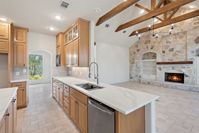 kitchen featuring tasteful backsplash, a fireplace, beamed ceiling, stainless steel dishwasher, and sink