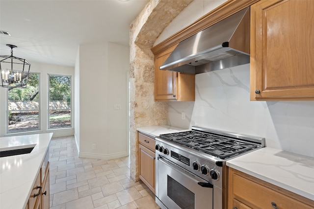 kitchen featuring backsplash, wall chimney exhaust hood, stainless steel stove, decorative light fixtures, and a notable chandelier