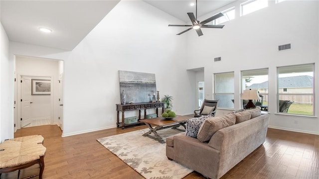 living room featuring wood-type flooring, a towering ceiling, and ceiling fan