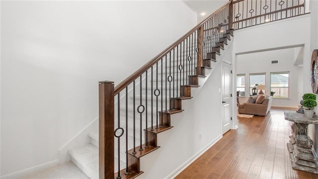 stairs featuring hardwood / wood-style floors and a high ceiling