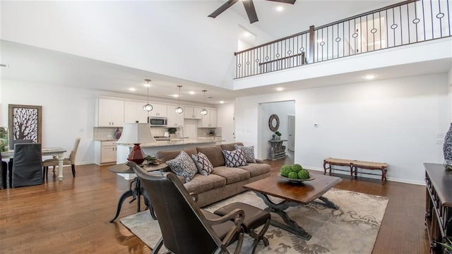 living room featuring dark hardwood / wood-style flooring, high vaulted ceiling, ceiling fan, and sink