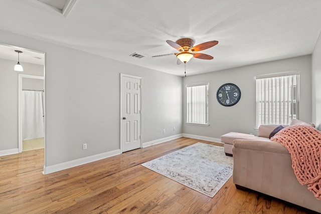 living room featuring light wood-type flooring, a textured ceiling, ceiling fan, and plenty of natural light