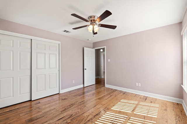 unfurnished bedroom with light wood-type flooring, ceiling fan, and a closet