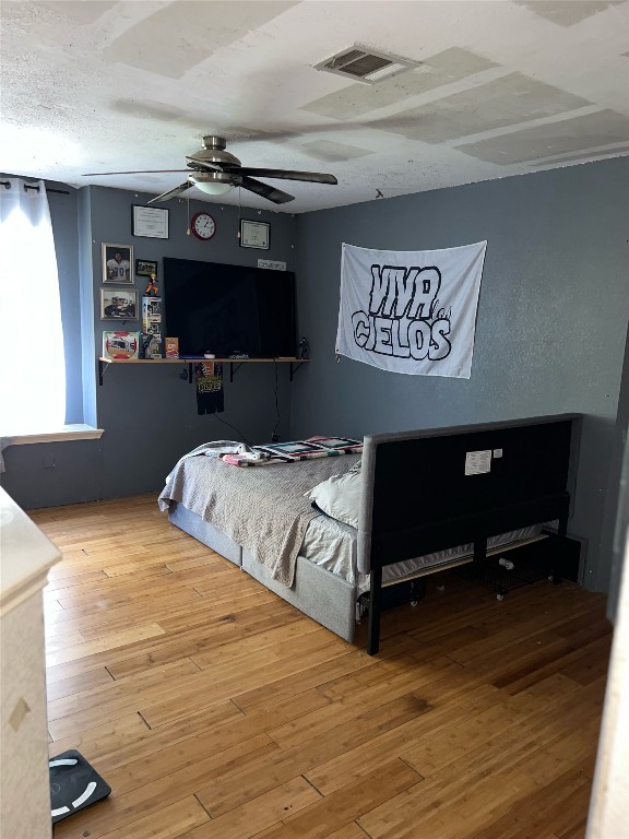 bedroom featuring wood-type flooring, ceiling fan, and a textured ceiling