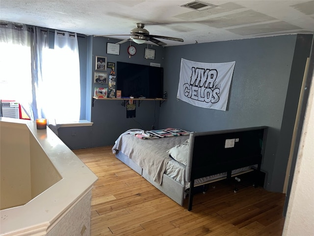 bedroom featuring ceiling fan, hardwood / wood-style flooring, and a textured ceiling