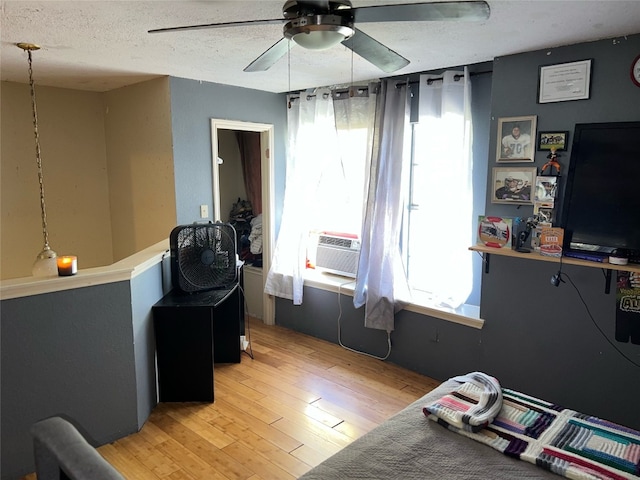 office space featuring ceiling fan, cooling unit, a textured ceiling, and light hardwood / wood-style flooring